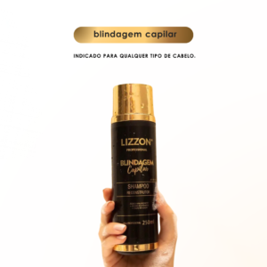 Uma mão segura um frasco preto e dourado de 250 ml de Shampoo Blindagem Capilar (homecare) em um fundo branco liso. O texto acima diz "blindagem capilar" e "Indicado para qualquer tipo de cabelo".